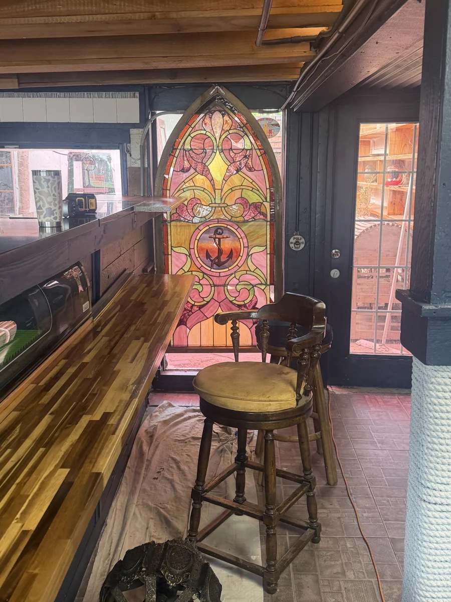 Amber and rose stained glass with an anchor beside an antique counter chair